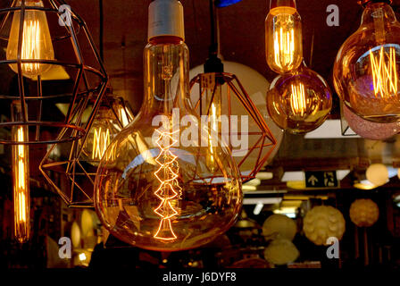 Glowing filaments in oversized light bulbs in shop window display, London Stock Photo