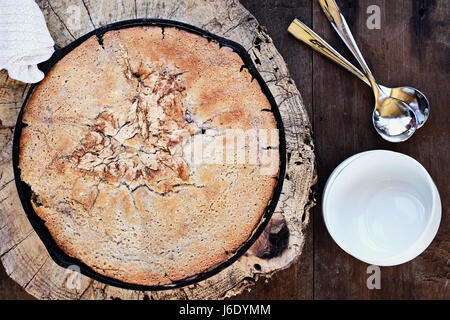 Above image of a blueberry and peach cobbler baked in a cast iron skillet over a rustic wood table top. Image shot from overhead. Perfect dessert for  Stock Photo