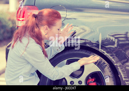Frustrated young woman checking pointing at car scratches and dents outdoors outside Stock Photo