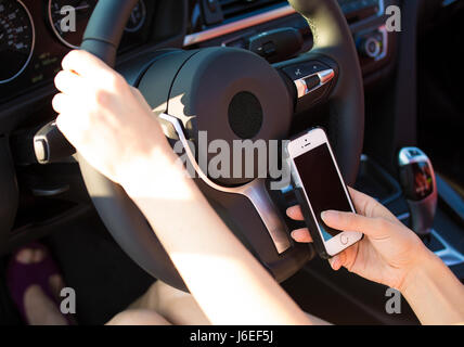 Closeup businesswoman, woman hands, sending text message on smart phone while driving to work. Traffic safety, rules, regulations concept. Bad driver  Stock Photo