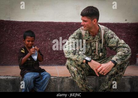 CHOLOMA, Honduras (Aug. 17, 2016) – U.S. Navy Lt. Cmdr. Patrick McKenna, a preventive medicine officer assigned to Navy Environmental Preventive Medicine Unit 2, takes a break with a local child from Choloma’s Monte Verde village during Southern Partnership Station 2016 (SPS-16). SPS-16 is an annual series of U.S. Navy deployments focused on subject matter expert exchanges with partner nation militaries and security forces in Central and South America and the Caribbean. U.S. military teams work with partner nation forces during naval-focused training exercises, military-to-military engagements Stock Photo