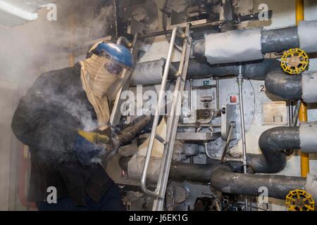 160817-N-XK809-050 EAST CHINA SEA (Aug. 17, 2016) Fireman Carlon Thorpe removes a burner valve from the number two boiler during a routine burner valve change out in the forward main machinery room of amphibious assault ship USS Bonhomme Richard (LHD 6). Bonhomme Richard, flagship of the Bonhomme Richard Expeditionary Strike Group, is operating in the U.S. 7th Fleet area of operations in support of security and stability in the Indo-Asia-Pacific region. (U.S. Navy photo by Mass Communication Specialist 3rd Class William Sykes/Released) Stock Photo