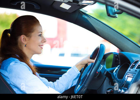 Portrait smiling, attractive brunette woman, buckled up, driving, testing her new black car, automobile, purchased at dealership, isolated street, cit Stock Photo