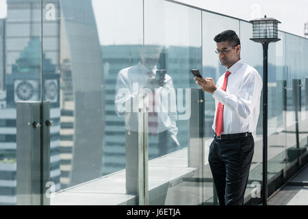 Businessman using phone on the top of a modern building Stock Photo