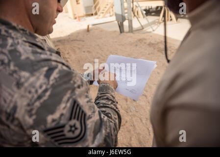 Tech. Sgt. Travis Monks, left, and Senior Airman Jurel Burton, heating, ventilation and air conditioning technicians with the 407th Expeditionary Civil Engineer Squadron, consult a construction plan during the installation of an air conditioning duct, May 4, 2017, in Southwest Asia. The new cooling system will provide cooled air to a crucial computer server that will power operations in the fight against ISIS. Monks is the NCO in charge of HVAC installs and Burton is an HVAC technician team lead. (U.S. Air Force photo by Staff Sgt. Alexander W. Riedel) Stock Photo