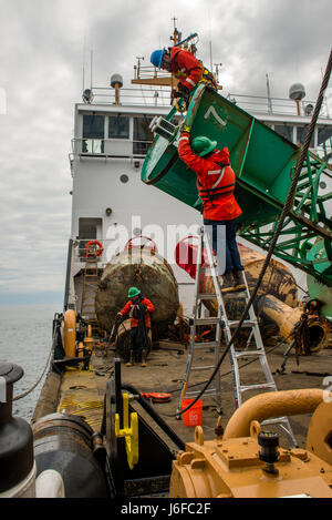 Petty Officer 1st Class Robert Swieciki (top) and Petty Officer 3rd Class Carlos Cabral (bottom) remove a light from the top of a buoy, Wednesday, May 10, 2017, aboard Coast Guard Cutter Oak. Coast Guard Cutter Oak is 225-foot buoy tender homeported in Newport, Rhode Island. (U.S Coast Guard photo by Petty Officer 3rd Class Andrew Barresi) Stock Photo