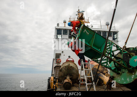 Petty Officer 1st Class Robert Swieciki (top) and Petty Officer 3rd Class Carlos Cabral (bottom) remove a light from the top of a buoy, Wednesday, May 10, 2017, aboard Coast Guard Cutter Oak. Coast Guard Cutter Oak is 225-foot buoy tender homeported in Newport, Rhode Island. (U.S Coast Guard photo by Petty Officer 3rd Class Andrew Barresi) Stock Photo