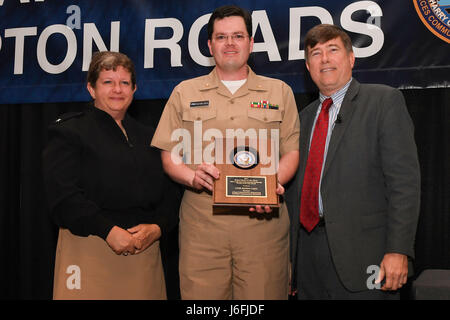 170517-N-GX781-065 NORFOLK (May 17th, 2017) - Rear Adm. Danelle Barrett, director, DON deputy chief information officer (Navy) and deputy director, Navy Cybersecurity, left, and Mr. Robert Foster, DON chief information officer, right, present DON Cyberspace/IT Person of the Year award to NAVSEA Cybersecurity Initiative Lt. Cmdr. Matthew R. Legler for coordinating with many stakeholders to ensure unity of effort and accomplishing the first Cyber Situational Awareness Alteration on a U.S. Navy ship in just three months when planners estimated that it would take 18. The purpose of the IT conferen Stock Photo