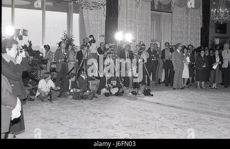 A group of personnel, including men and women, observe and operate cameras in a controlled indoor setting, demonstrating teamwork, coordination, and technical operation during a media or operational briefing. Stock Photo