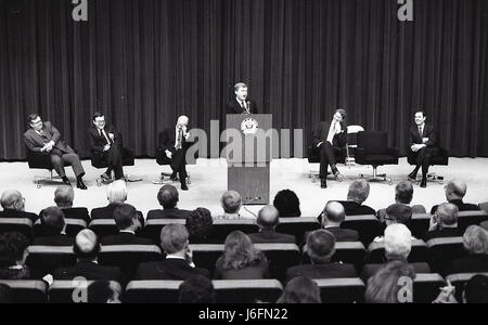 A speaker addresses an audience from a podium on stage while multiple individuals observe and listen during a formal event. Stock Photo