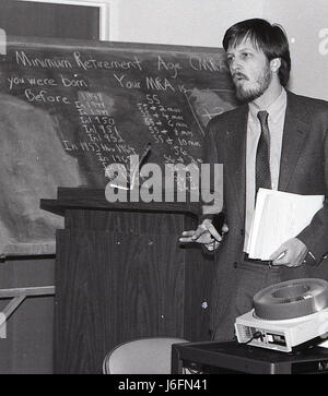 A man delivers a speech in front of a projector, presenting information to a group in a professional or military setting. Stock Photo