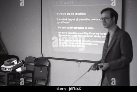 A man delivers a speech in front of a screen to an audience, likely presenting information or training content in a professional or military setting. Stock Photo