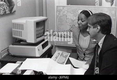 Two military personnel review information on a computer, likely analyzing operational or administrative data in a professional setting. Stock Photo