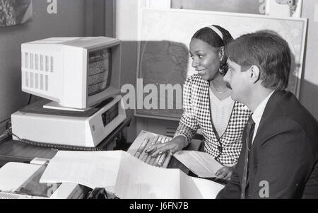 Two military staff members review information on a computer, coordinating tasks, planning operations, and analyzing data during office or mission preparation. Stock Photo