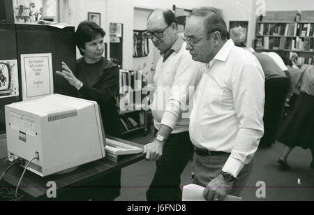 Two men and a woman examine data on a computer screen, collaborating on analysis, reviewing information, and performing tasks related to operations or training within a work environment. Stock Photo
