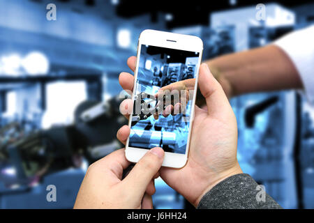 Cyber communication and robotic concepts. Industrial 4.0 Cyber Physical Systems concept. hand holding smart phone and robot and blur Engineerer human  Stock Photo