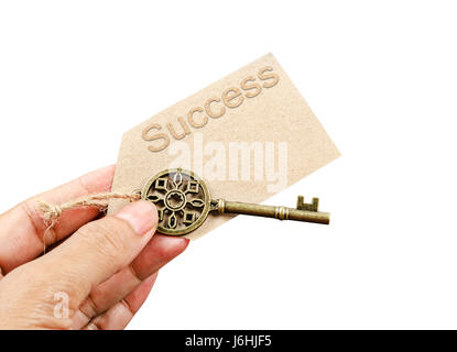 Hand holding metal vintage key with Success tag card isolated on white background. Save clipping path. Stock Photo