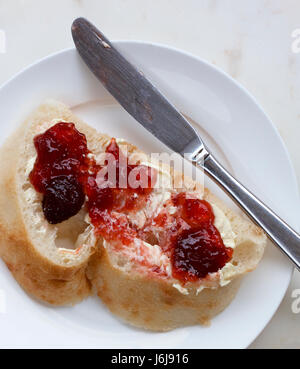 Slice of buttered turkish bread on a plate with a knife. Stock Photo