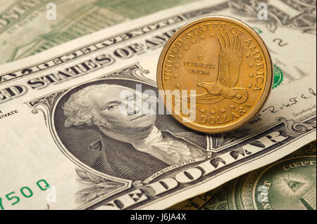 one dollar coin of US currency laying on one dollar banknote Stock Photo