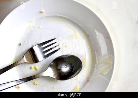 Empty dirty plate after a meal with a spoon and fork. Stock Photo
