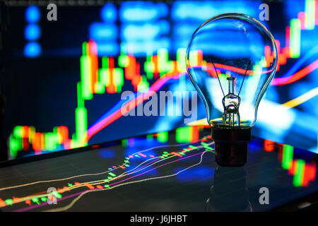 Light bulb stand on graph tablet screen with stock market graph background , idea concept Stock Photo