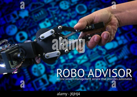 Cyber communication and robotic concepts. robo advisor concept. Robot and Engineer human holding hand with handshake and blur wealth management icons  Stock Photo