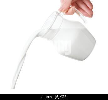 milk from jug pouring isolated on white background. Pouring milk from transparent glass pitcher Stock Photo