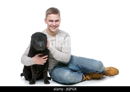 Handsome young man hugging black shar pei dog. Studio shot isolated on white background. Copy space. Stock Photo