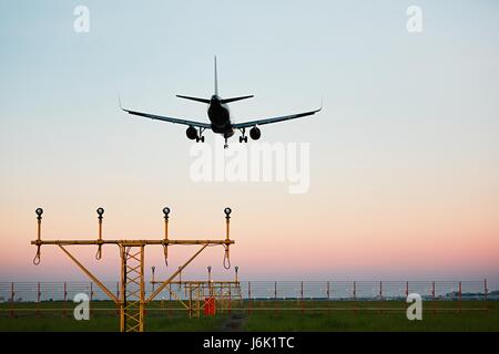 Airplane landing at the airport during colorful sunset. Stock Photo