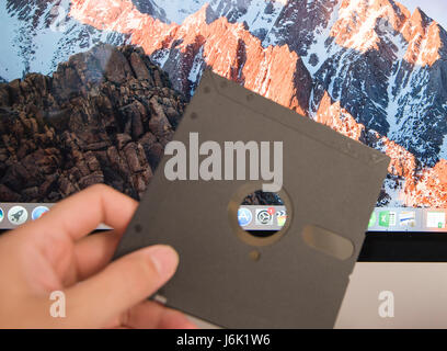 Old 5 1/4" floppy disk against settings icon of new apple computer Stock Photo