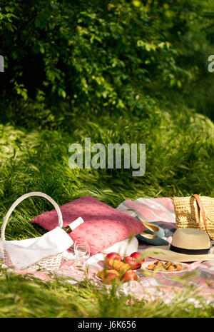 Summer picnic in the forest on the grass. Wine, fruit and croissants. Selective focus. Stock Photo