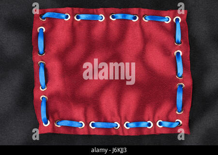 Frame made of blue ribbon inserted into a red fabric. View from above Stock Photo