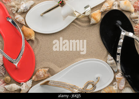Frame, four pairs slippers in the sand beach. View from above Stock Photo