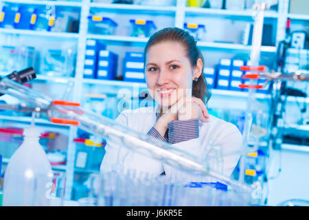 Attractive young female scientist working in laboratory.  Woman scientist looking at a red test tube in a lab. Young woman in chemical lab Stock Photo