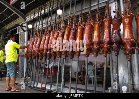 Quezon City, Philippines. 21st May, 2017. A man scrapes leftover hair from cooked lechon (roasted pig) with a knife during the La Loma Lechon festival in Quezon City, east of Manila, Philippines on Sunday, May 21, 2017. The festival, whose main highlight is the parade of lechon dressed in different costumes, is held every third Sunday of May, coincides with the Feast of Nuestro Señor de Salvacion, and has been a tradition in the area for more than fifty years. Credit: Richard James M. Mendoza/Pacific Press/Alamy Live News Stock Photo