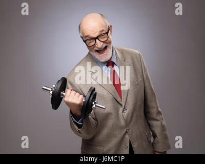 Happy funny senior man in suit with dumbbell, power concept Stock Photo