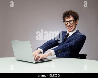 Funny business man geek using laptop with evil genius facial expression Stock Photo