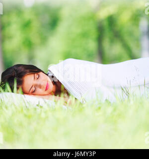 Beautiful young woman sleeping on grass outdoors Stock Photo