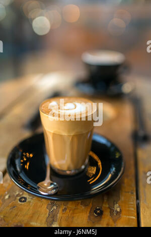 Cup of hot piccolo latte coffee on rustic wooden table close-up. Low depth of field Stock Photo