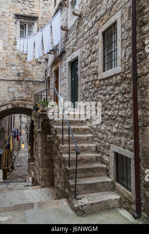 A typically rustic narrow street in the old town of Dubrovnik in the South of the Dalamatia region of Croatia.  Pretty windows combine with potted pla Stock Photo