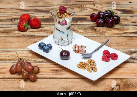 In a glass there is flat cheese with nuts and raspberries Stock Photo