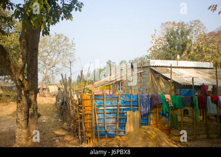 Newly built house of poor farmer in province Angra Pradesh: fence, drying clothes, sitting on pole house crow (Corvus splendens ). Stock Photo