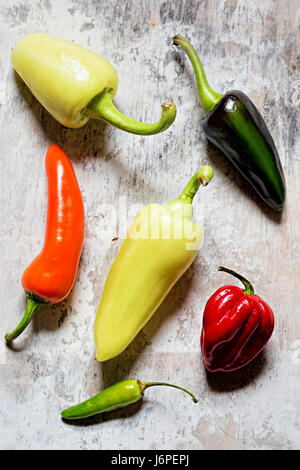 Green, red, yellow and orange peppers on white background