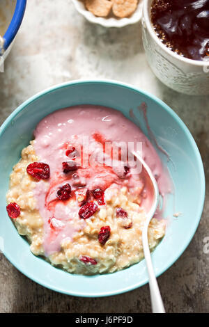 Breakfast porridge with mashed bananas, cherry yoghurt, dried cranberries with earl grey tea Stock Photo