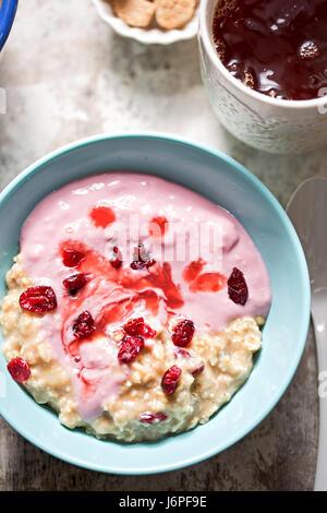 Breakfast porridge with mashed bananas, cherry yoghurt, dried cranberries with earl grey tea Stock Photo
