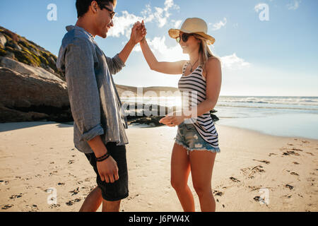 Shot of young man and woman dancing on the beach on a summer day. Romantic young couple dancing on the beach. Stock Photo