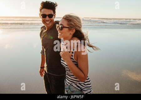 Portrait of romantic young couple walking on sea shore. Man and woman on beach holiday during summertime. Stock Photo