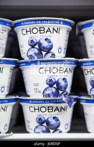 packages of Chobani brand yogurt on the shelves of a refrigerator case ...