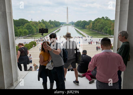 tourists taking selfies looking out of the lincoln memorial along the national mall and reflecting pool Washington DC USA Stock Photo