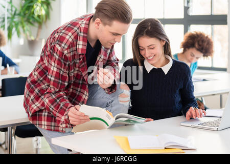 Friendly student helping his classmate by explaining and showing Stock Photo